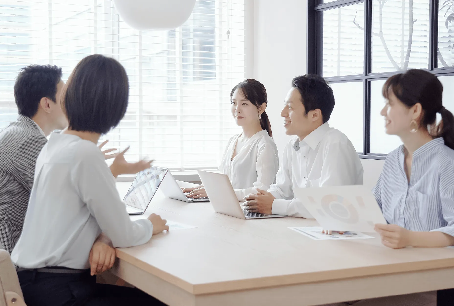 会議室で資料を見ながら話し合う人たち