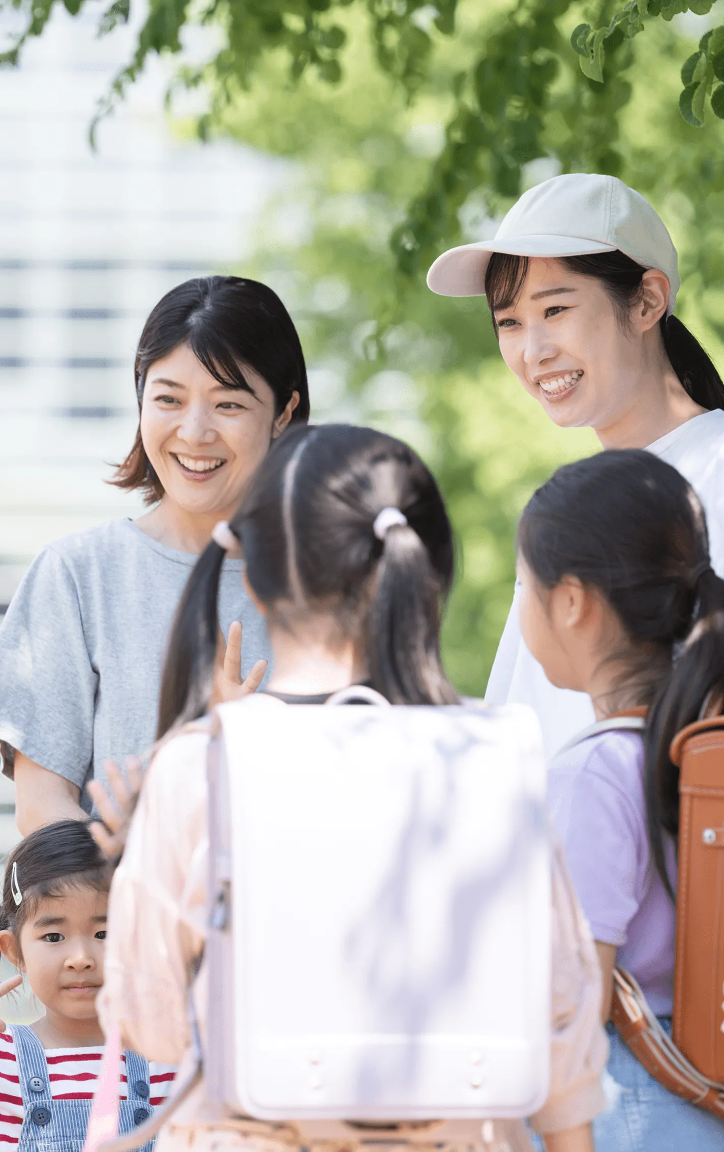 ランドセルを背負った子どもたちと、笑顔で話す保護者たち