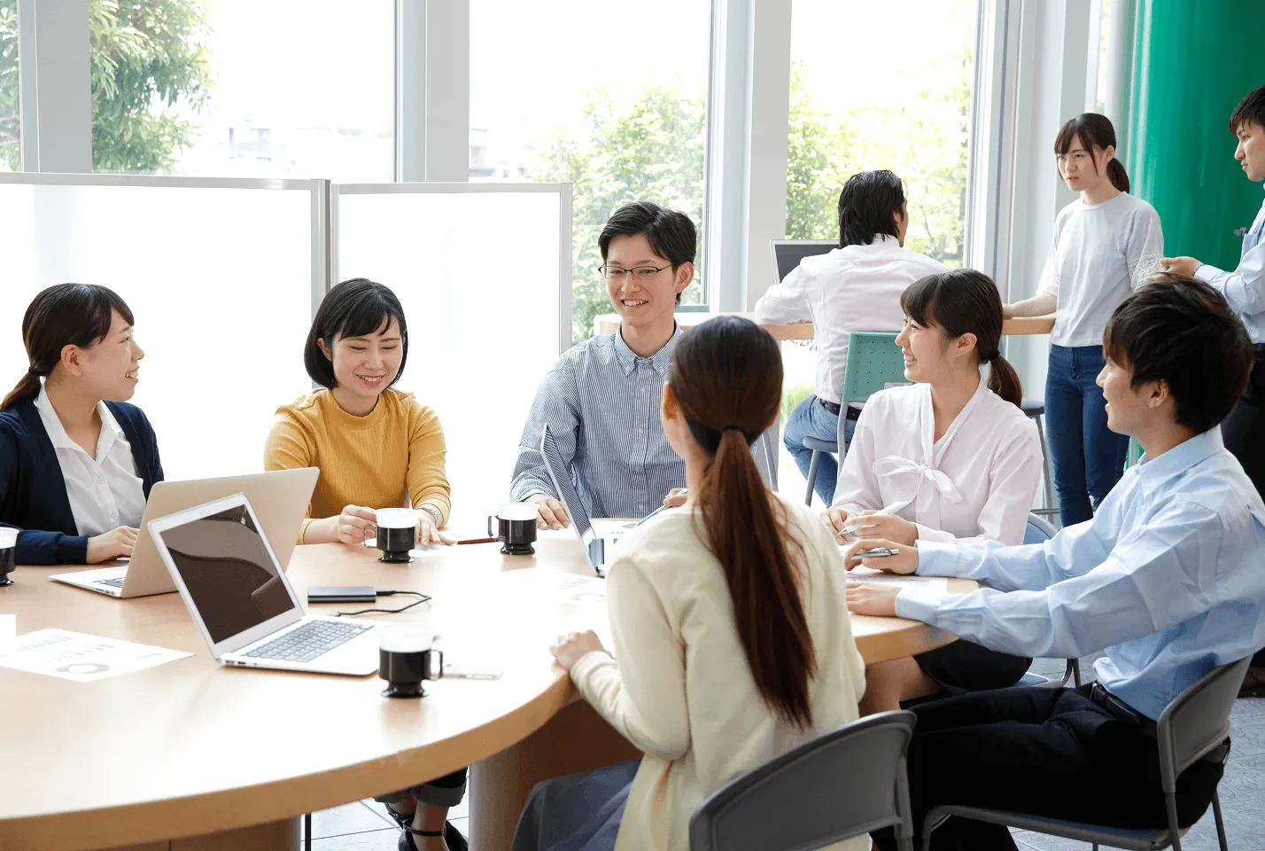 円卓を囲み、パソコンを見ながら談笑する人たち